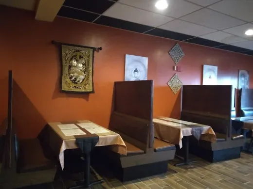 Pada Thai's dining room with terracotta walls, live plants, and wooden booth seating
